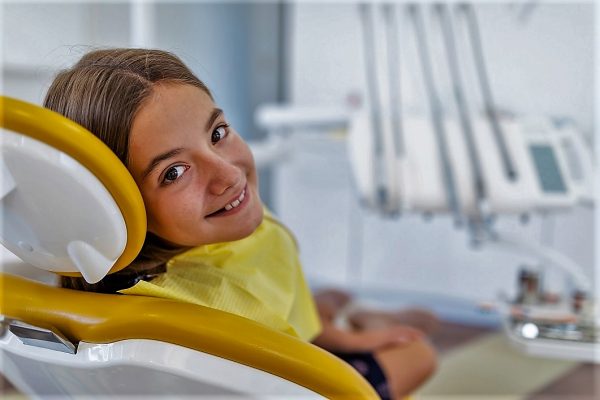 Beautiful smiling girl in dental office, waiting for dental treatment